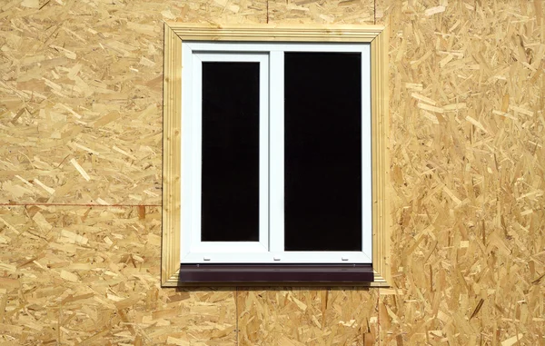 Muur van houten panelen met witte kunststof venster close-up — Stockfoto