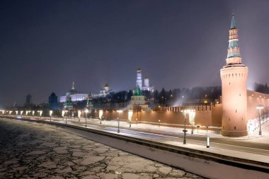 Moskova Nehri buzla kaplı ve Kremlin kırmızı tuğlalı duvar. Kuleleri tepede. Gece görüşü olan tatil caddesi aydınlatma manzaralı.