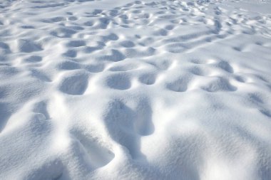 Güneşli kış gününde açık beyaz karla kaplı bir sürü insan ayak izi olan kar tarlası.