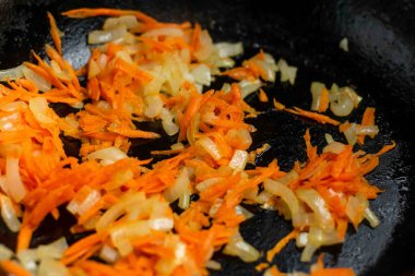 Yakın planda havuçlu kızarmış soğan. Yemek pişirmek için malzemelerin hazırlanması.