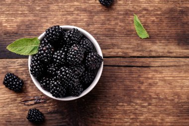 Beyaz kasede böğürtlenler ve yakın plan üzerinde nane yaprakları..