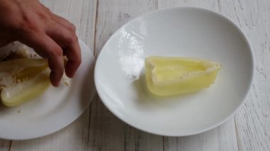 Bir adamın eli ahşap bir yüzeye yarım dolma biber koyar. Yemek hazırlığı.