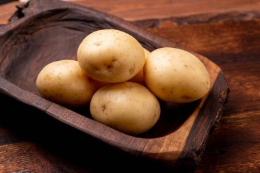 Ahşap arka planda büyük, taze patates yığınları..