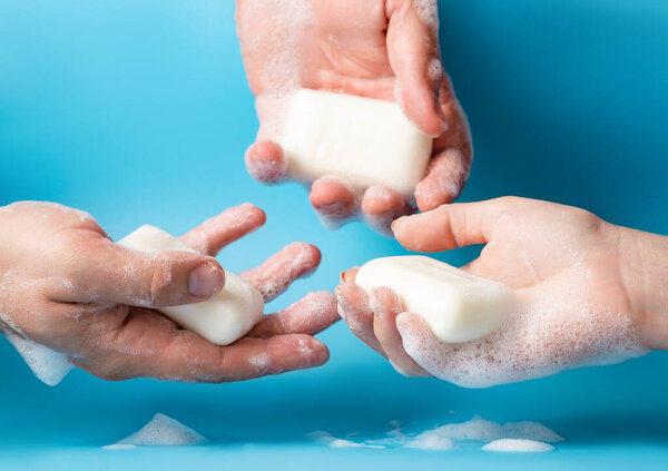Global Handwashing Day, personal hygiene concept. Three hands in soapy foam with soap on a blue background on a light blue background.