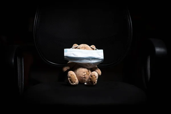 Teddybär Mit Aufgesetzter Medizinischer Maske Auf Einem Bürostuhl Auf Schwarzem — Stockfoto