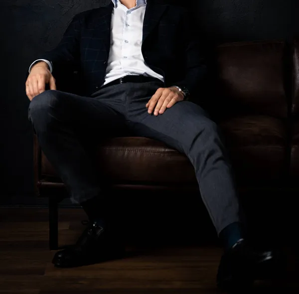 Tanınmayan stil sahibi maço adam karanlıkta koltukta rahatça oturuyor..