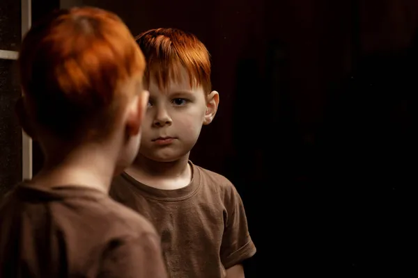 Genç Kızıl Saçlı Bir Çocuk Koyu Bir Arka Planda Aynada — Stok fotoğraf