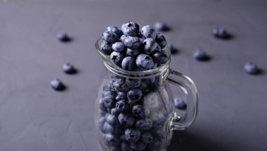 Gri beton arka planda cam sürahide yabanmersini. Meyvelerin faydaları, vejetaryenlik kavramı.