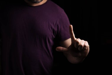 Tişörtlü bir adam arka planda işaret parmağını tutuyor..
