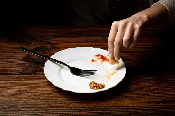 女性は暗い部屋で白い皿から食べ物を食べる 最後の食事の概念 — ストック写真