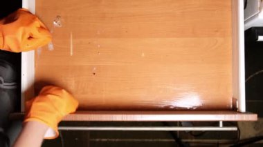 Lastik eldivenli bir kadın mutfak çekmecesini yıkıyor. Evi temizliyorum. Yukarıdan görüntüle.