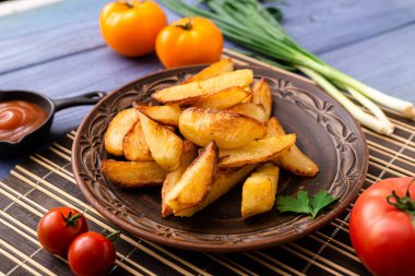 Masadaki tabakta farklı sebzelerle birlikte büyük parçalar halinde kızarmış patates..