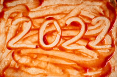 Yeni yıl 2022 numara domates soslu pişmiş pizzanın üzerine yazılmış..