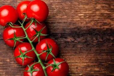 Kahverengi ahşap arka planda taze kiraz domatesleri dalı.