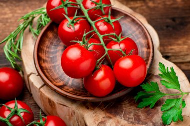 Kahverengi ahşap zemin üzerinde yeşillikler olan taze domatesler..