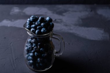 Koyu arkaplanda yabanmersinli cam sürahi. Meyvelerin faydaları, vejetaryenlik kavramı.