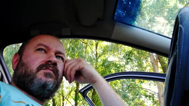 Unshaven Man Sits Rests Parked Car Summer Backdrop Green Trees — Stock Video