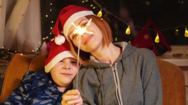 Anne ve oğlu yeni yıl şapkalarında yanan maytapla. Yeni yıl, Noel havası.