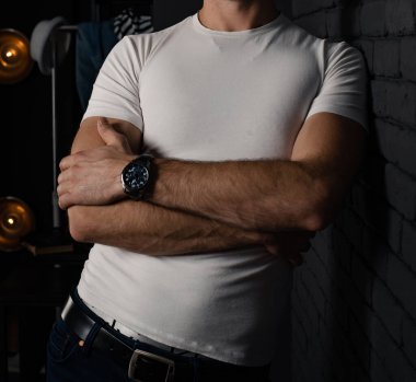Beyaz tişörtlü, elinde siyah bir saat olan tanınmamış bir adam..