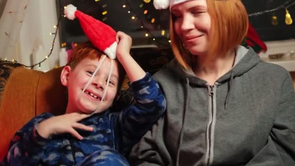 新的一年里 一个小男孩和他的母亲坐在沙发上笑着 — 图库视频影像