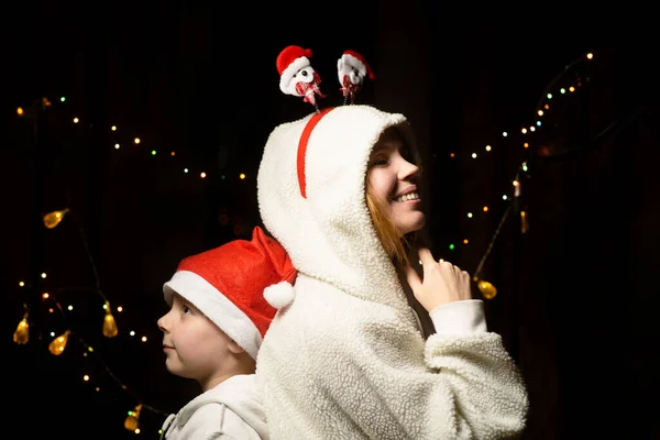 Mom and son make wishes for the new year. A woman and a young boy stand with their backs to each other in New Year\'s hats