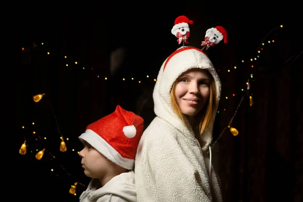 新年の光を背景に 女性と若い男の子が新年の帽子の中で横に立って笑顔 — ストック写真