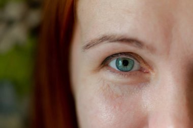 Makyajsız, kızıl saçlı bir kadının gözüyle çekici bir yüz..