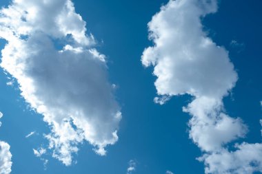 Açık güneşli havada mavi gökyüzünde koyu beyaz bulutlar.