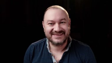 Tıraşsız sıradan bir adamın gülüşünün portresi. Karanlık arka plan. Mutlu yüz..