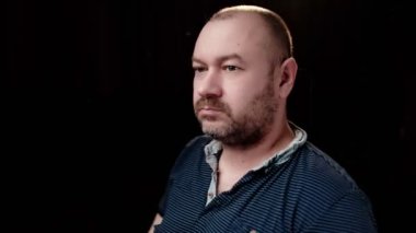 Orta yaşlı bir adam karanlık bir arka plana doğru dönüyor..