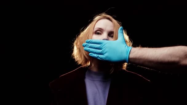 女性の口はゴム手袋の手で覆われていた 暗い背景 沈黙陰謀論 — ストック動画