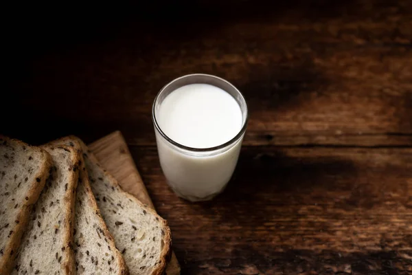 Bicchiere Pieno Latte Pane Sullo Sfondo Offuscato Fondo Legno Scuro — Foto Stock