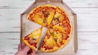 Kutudaki pizza dönüyor. Hareketi durdur. Pizza dilimleri erkek eli tarafından alınır. Fast food.