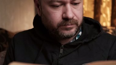 Orta yaşlı bir adam kitap okuyor. Tıraşsız adam. Bir kitapla rahatlamak..