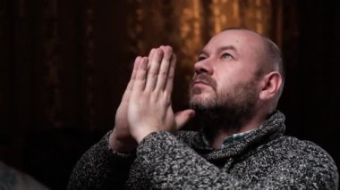 Orta yaşlı bir adam dua etmek ve dua etmek için ellerini katladı. Tanrı 'yla konuşmak. Ev ortamı.