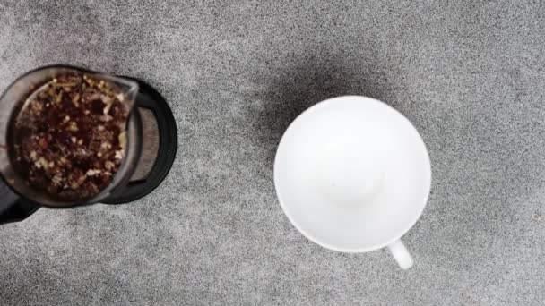 茶壶里的草药茶倒入桌上的杯子里 顶部视图 — 图库视频影像