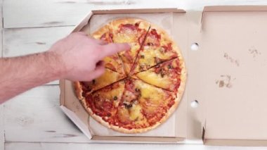 Karton bir kutuda pizza manzarası. El gösteriyor ki, pizza parçalarını sayıyor..