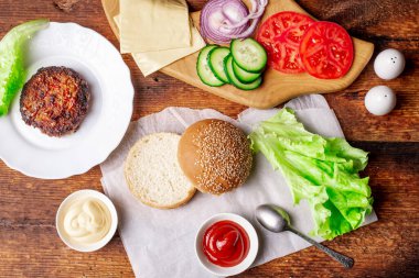 Klasik bir hamburger için gerekli malzemeler. Izgara et, sebze, sebze, susamlı ekmeğin yanında soslar. Ahşap arka plan. Hamburger mi çizburger mi?.
