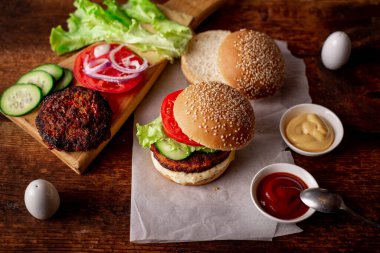 Ev yapımı hamburger ya da çizburger. Klasik bir hamburger için farklı malzemeler. Ahşap arka plan. Yiyecek konsepti.