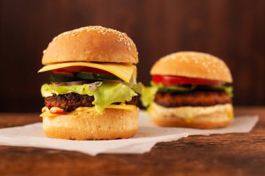Ahşap arka planda iki hamburger. Büyük ve küçük çizburger. Hamburger günü..