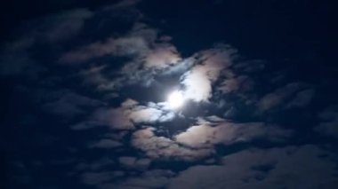 Gökyüzünde parlayan ay ve hareket eden bulutlar. Zaman ayarlı. Gece gökyüzü manzarası.