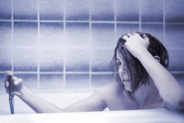 Şehvetli orta yaşlı kadın banyo yapıyor ve cep telefonuyla video iletişimiyle iletişim kuruyor. Çıplak selfie, samimi fotoğraf konsepti. Online randevular, aşk oyunları. Mavi tonlama.