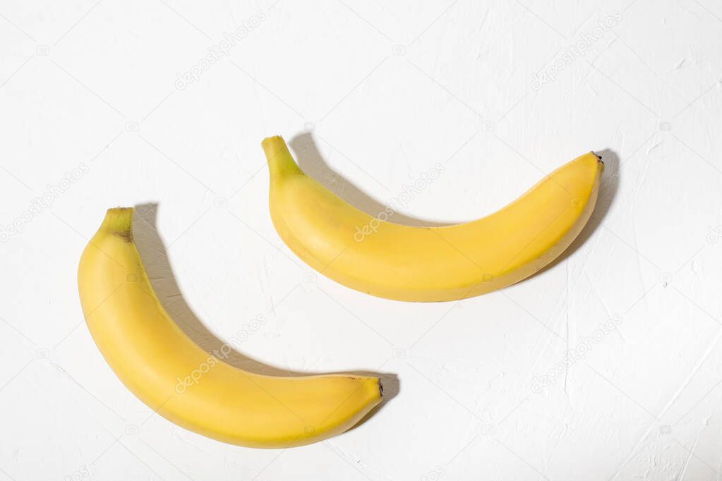 Two bananas on a white background. Whole unpeeled natural banana.