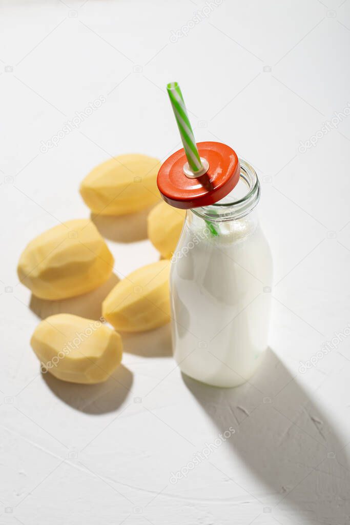 Potato milk concept. Bottle with potato milk on a white background. An alternative to animal products. Vegan food.