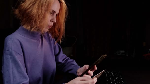 電話と銀行カードを持つ女性 暗い背景 40歳の赤髪の女性 オンラインショッピングのコンセプト — ストック動画