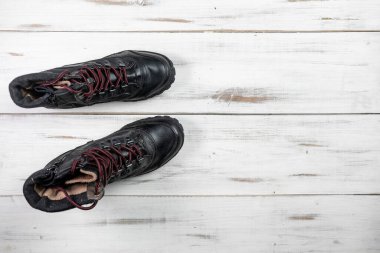 Hafif ahşap arka planda bağcıkları olan siyah rahat kadın çizmeleri..