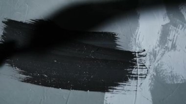 Bir boya fırçası yüzeyi siyah boyayla boyar. Boyama işini yürütüyorum. Dekorasyon, ev yenileme konsepti.