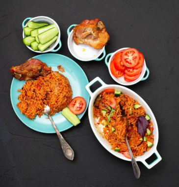 Tavuklu jollof pilavı tabakta. Domatesli pilav, soğan, baharat. Geleneksel Nijerya yemekleri. Koyu arkaplan.