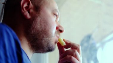 Bir adam düşüncesizce yer ve pencereden dışarı bakar. Kırklı yaşlarda, traşsız orta yaşlı bir adam. Aşırı yemek, aşırı stres konsepti.