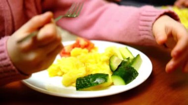 Kız patatesleri salatalık ve sosisle yiyor. Yemek, öğle yemeği..